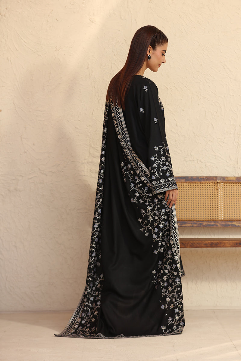 Woman wearing a black and white patterned outfit against a beige wall.