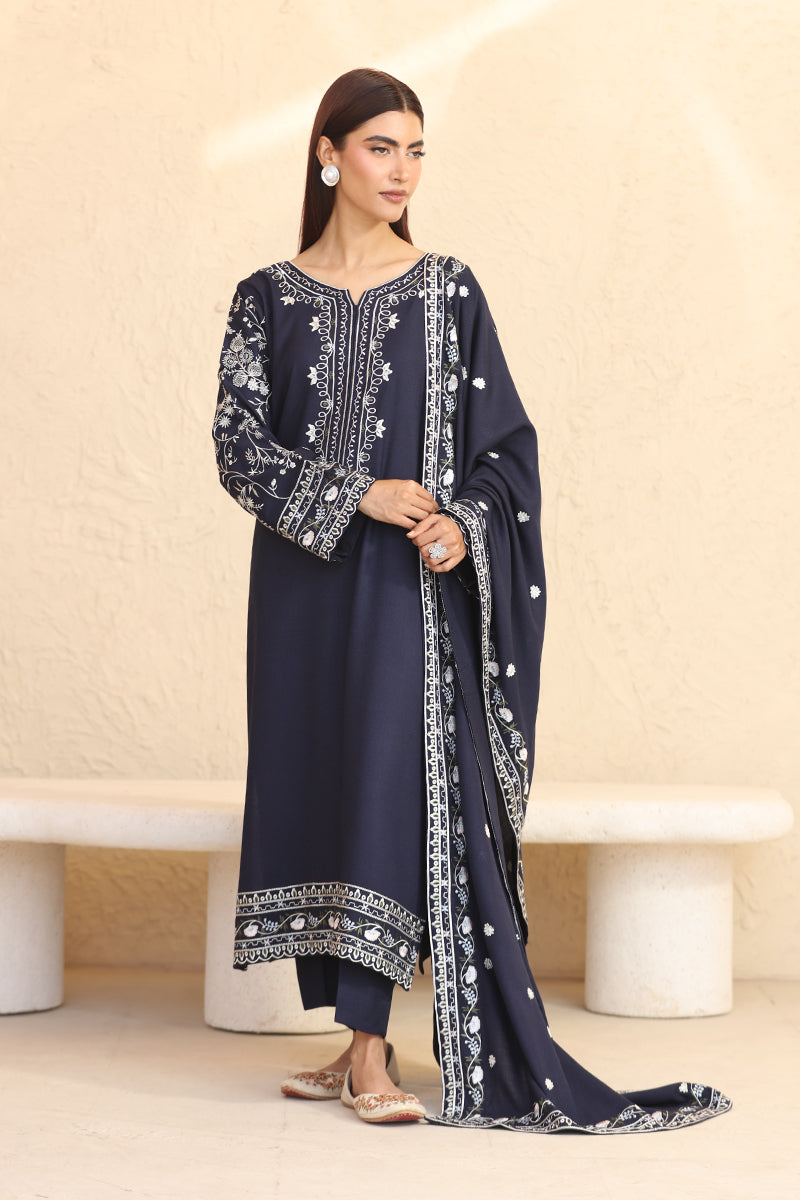 Woman wearing a navy blue embroidered outfit with a beige background