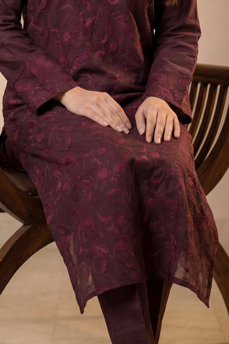Women wearing a Purple floral dress sitting on a wooden chair.