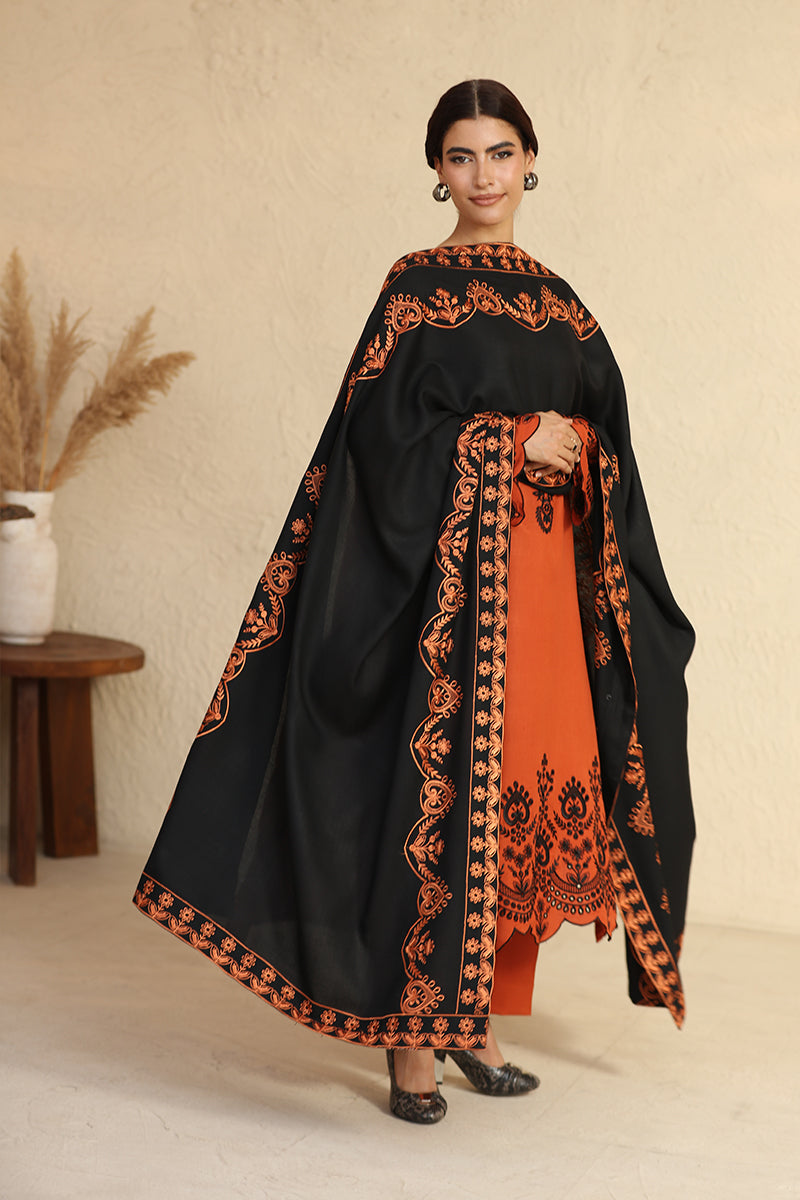 Woman wearing a black and orange embroidered outfit against a beige background