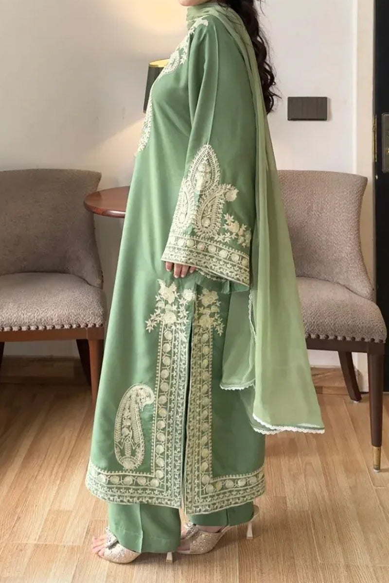 Person wearing a green embroidered traditional outfit indoors.