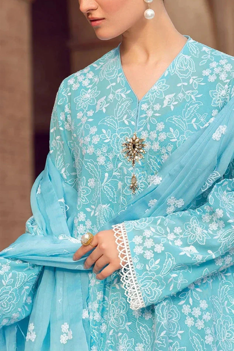 Close-up of a person wearing a light blue embroidered traditional outfit with a blurred background