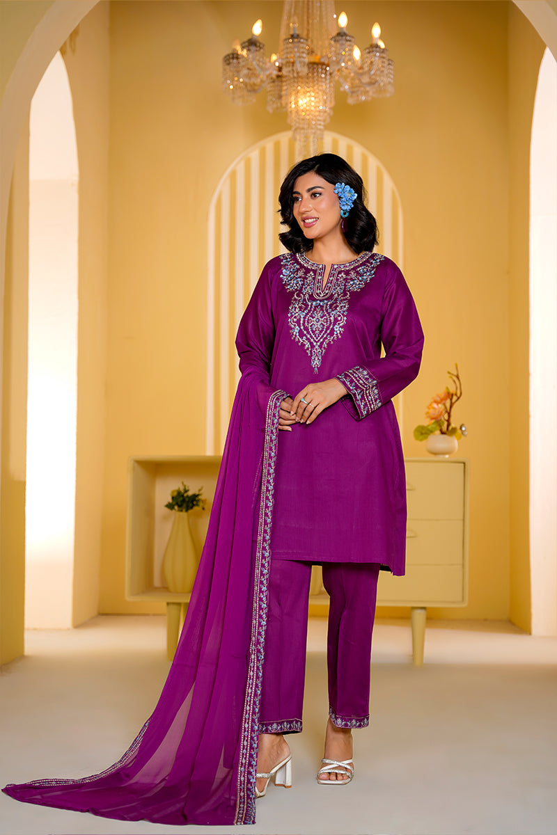 Woman in a purple traditional outfit with intricate designs in a decorated room.
