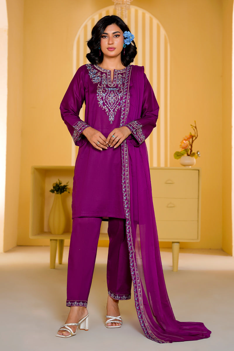 Woman wearing a purple embroidered outfit in a decorated room.