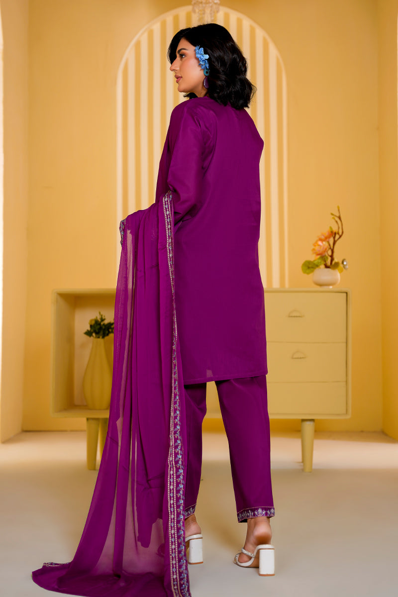 Woman in a purple outfit standing in a room with a yellow wall and white floor.