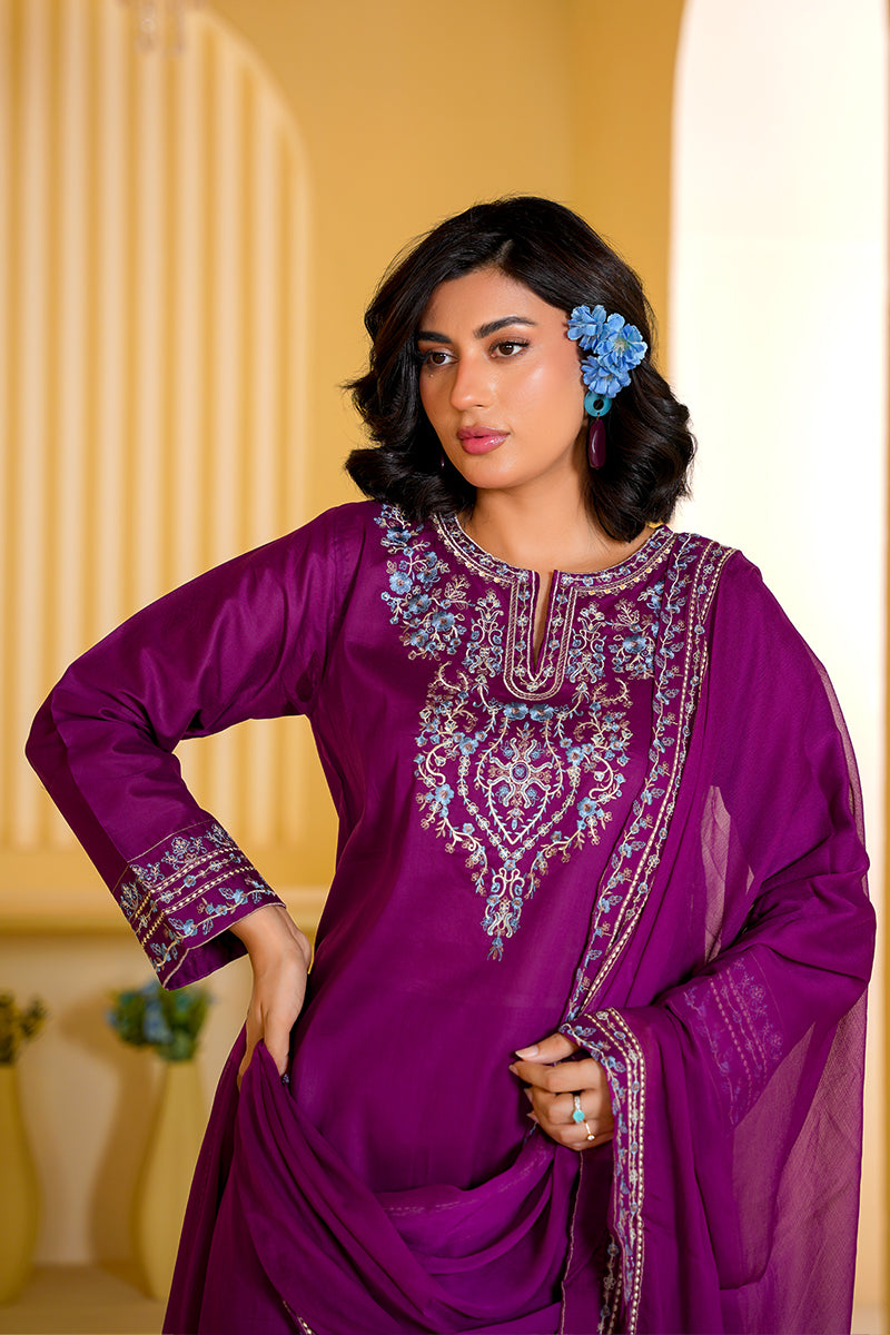 Woman wearing a purple embroidered traditional outfit with a yellow background