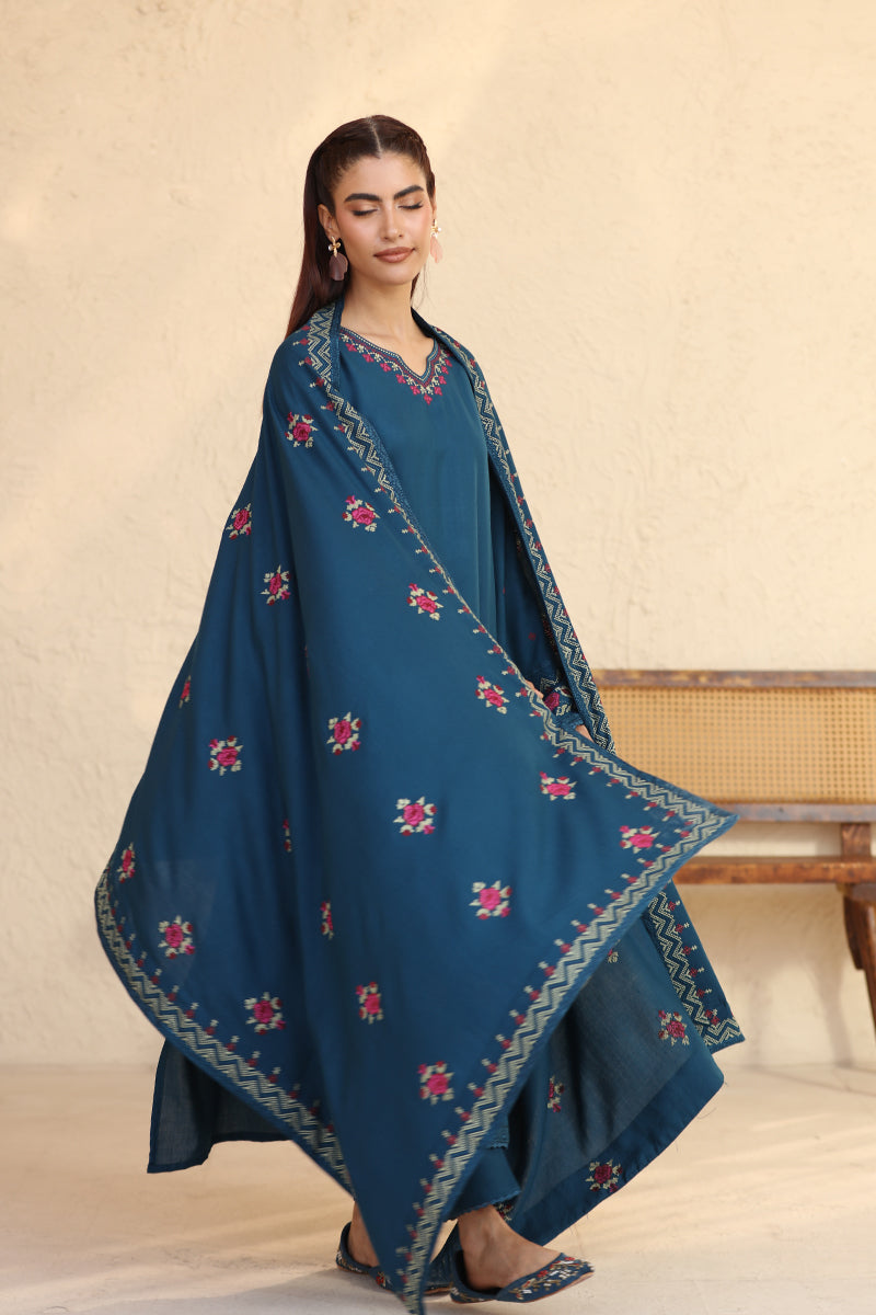 Woman wearing a blue embroidered traditional outfit on a beige background