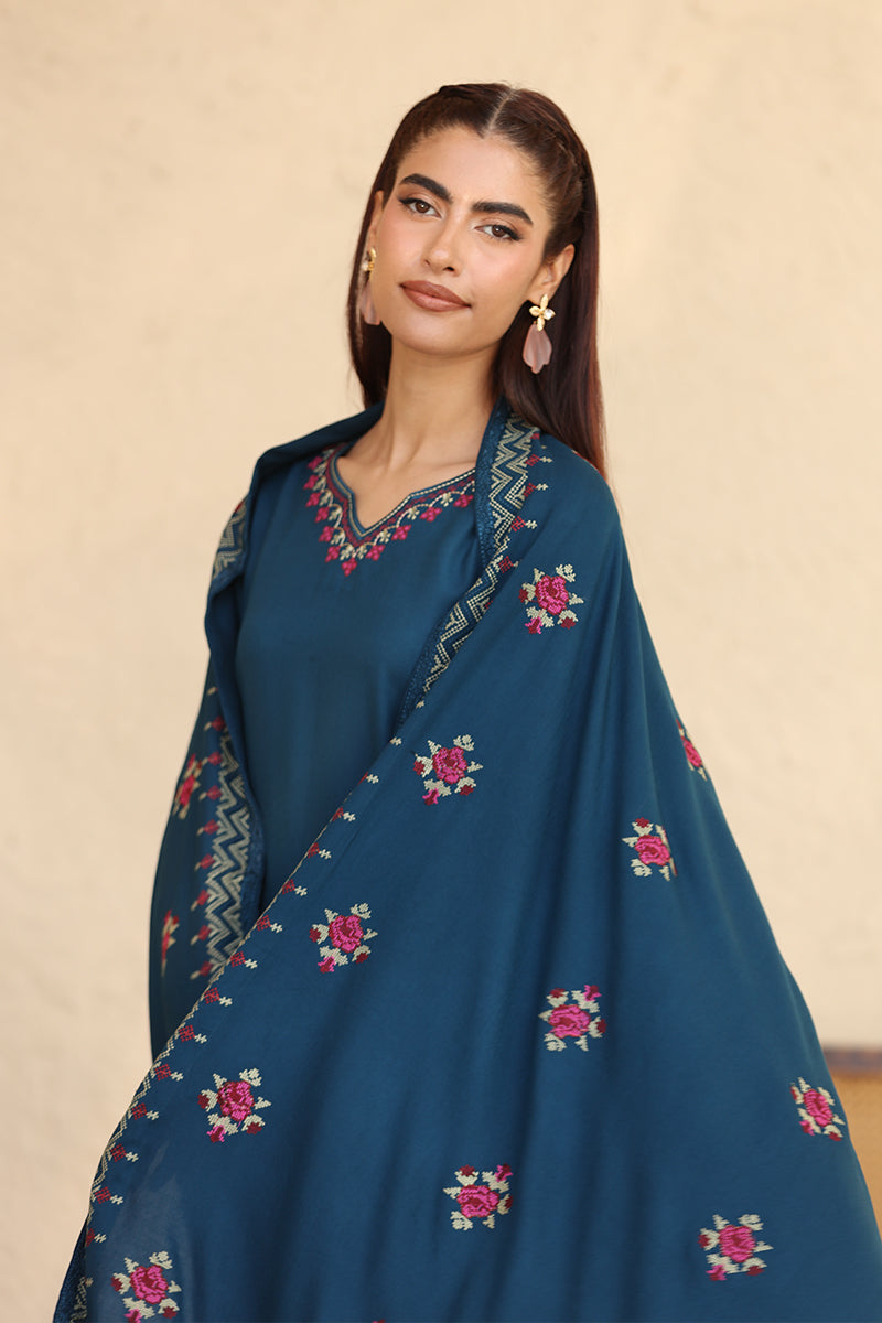 Woman wearing a blue embroidered traditional outfit on a beige background