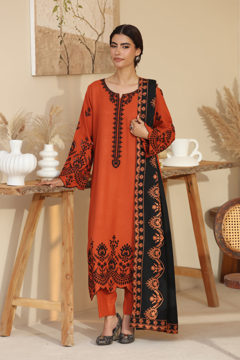 Woman wearing an orange and black embroidered dress in a home setting.
