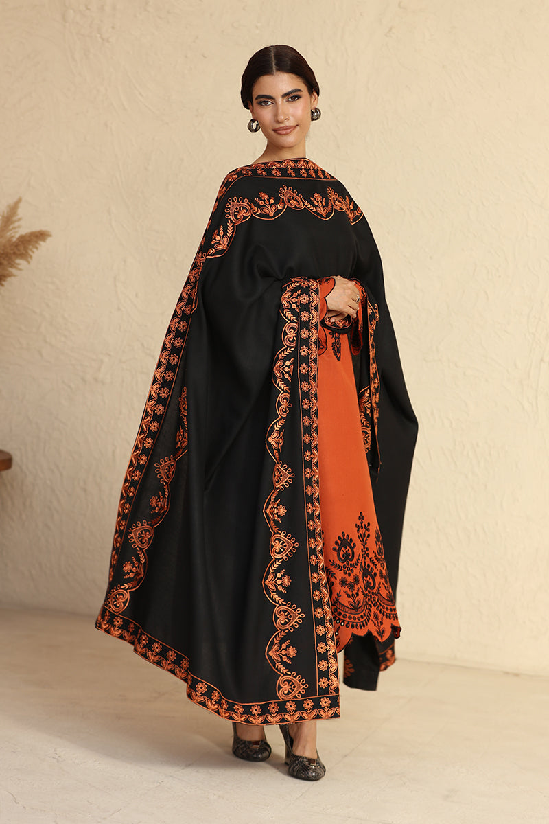 Woman wearing a black and orange embroidered dress against a beige background