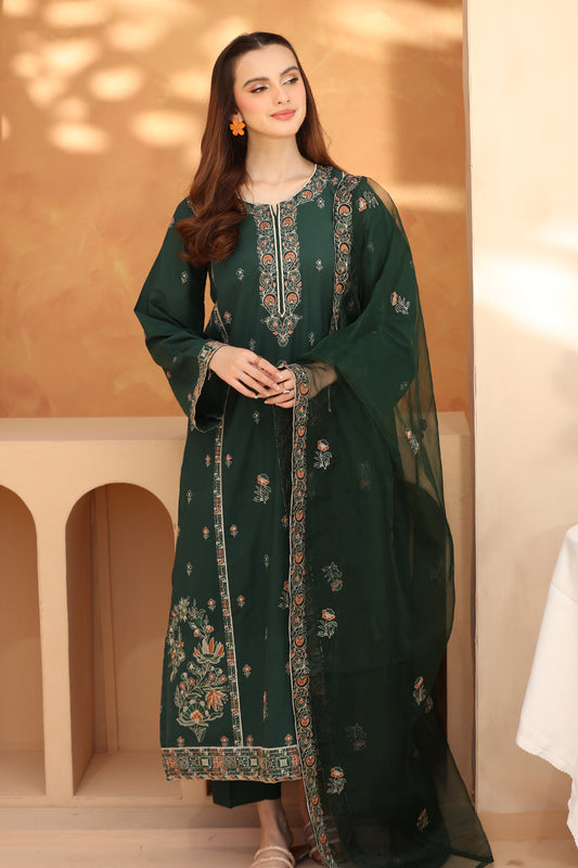 Woman wearing a dark green embroidered traditional outfit in a softly lit room.