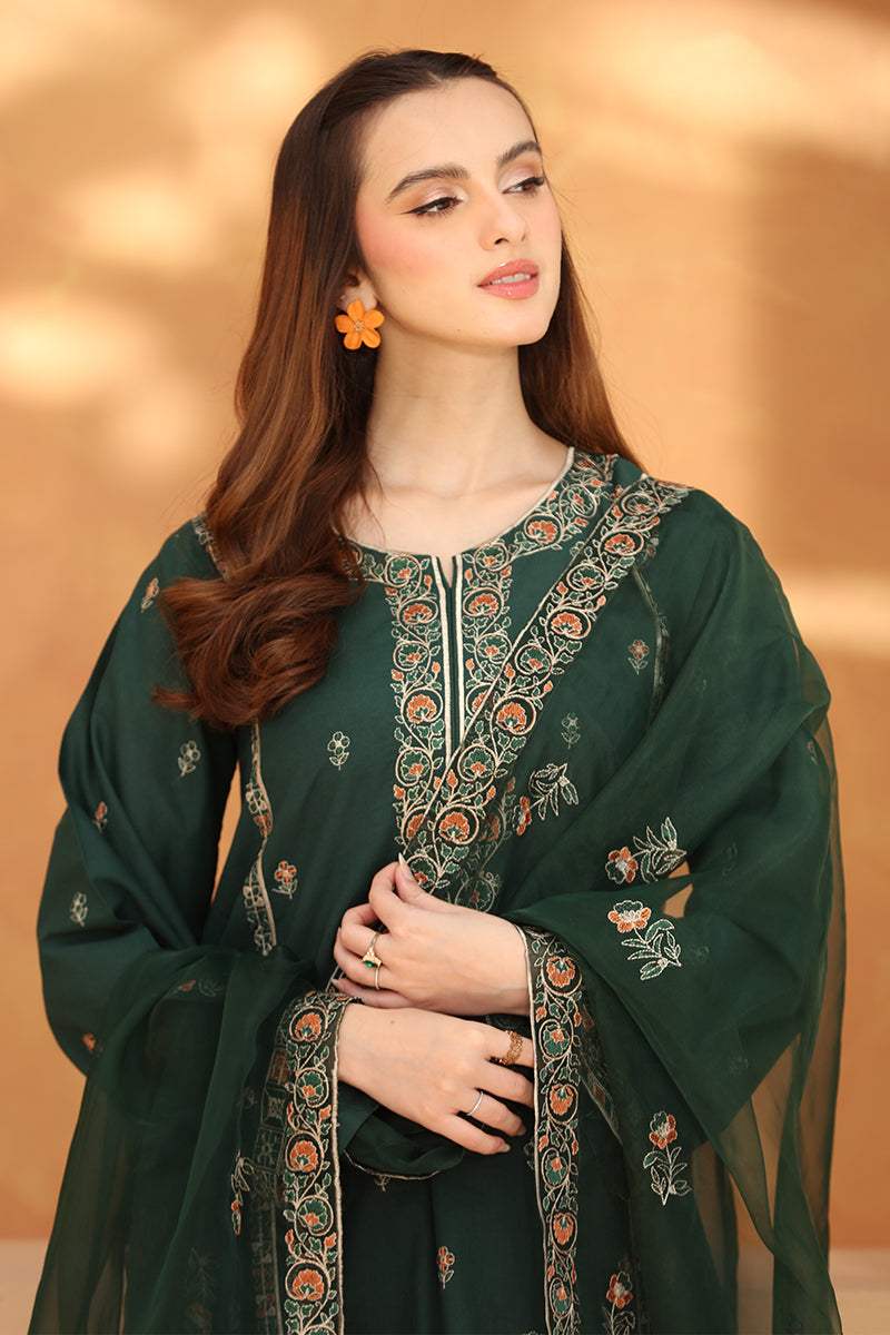Woman wearing a green embroidered traditional outfit with a beige background