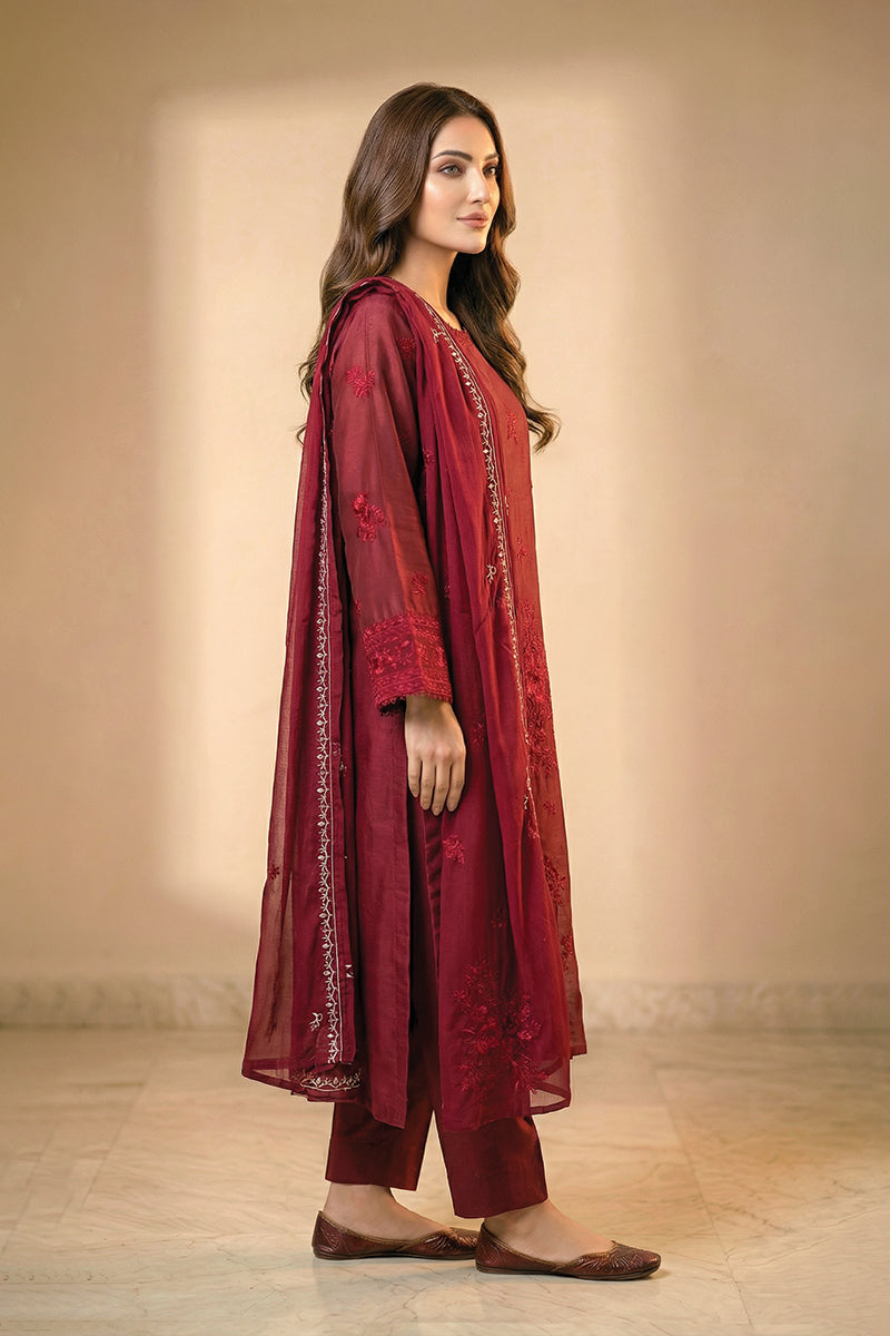 Woman wearing a maroon traditional outfit with a plain background