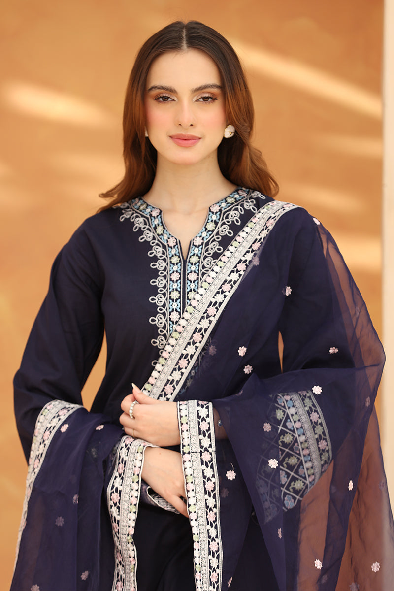 Woman wearing a navy blue embroidered traditional outfit with a sheer dupatta against a beige background