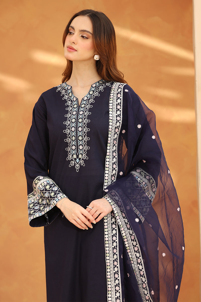 Woman wearing a navy blue embroidered outfit with a matching dupatta against an orange background