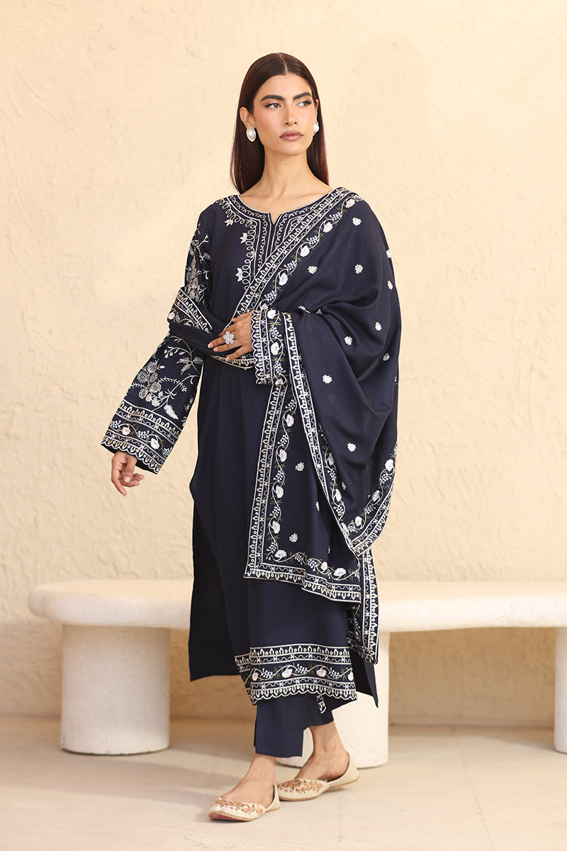 Woman wearing a navy blue embroidered outfit with a beige background