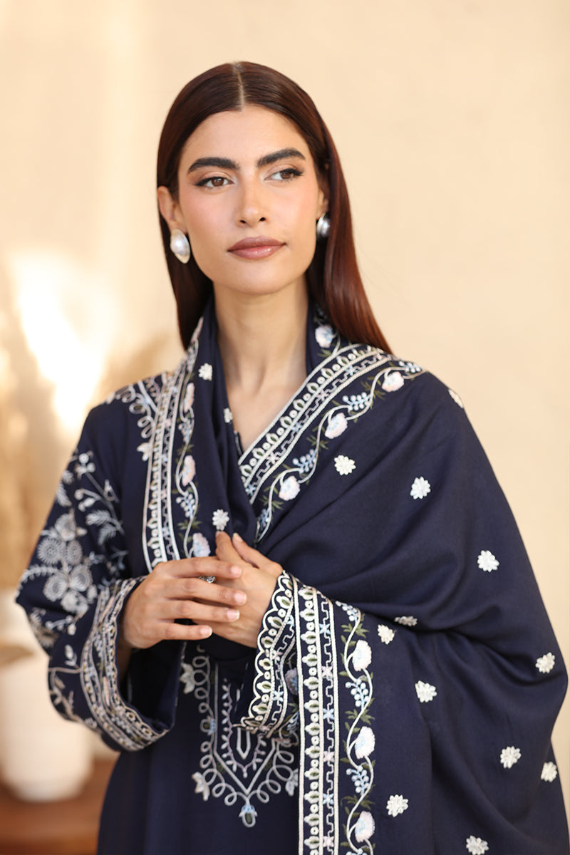 Woman wearing a navy blue embroidered shawl against a beige background