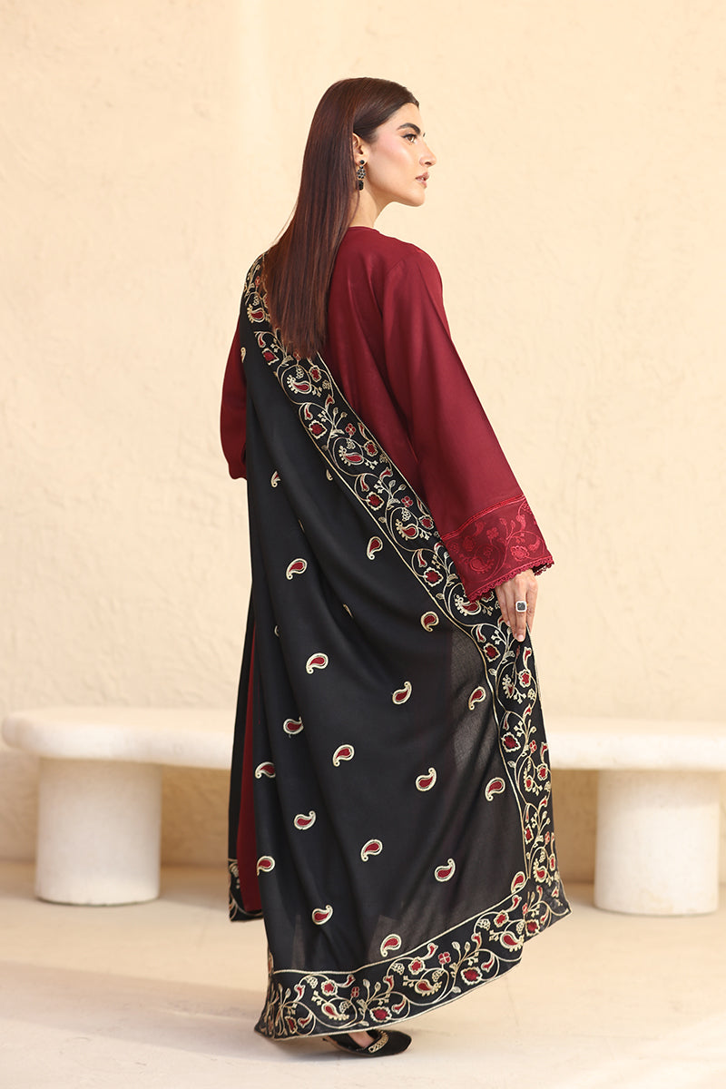 Woman wearing a black saree with red blouse against a beige background