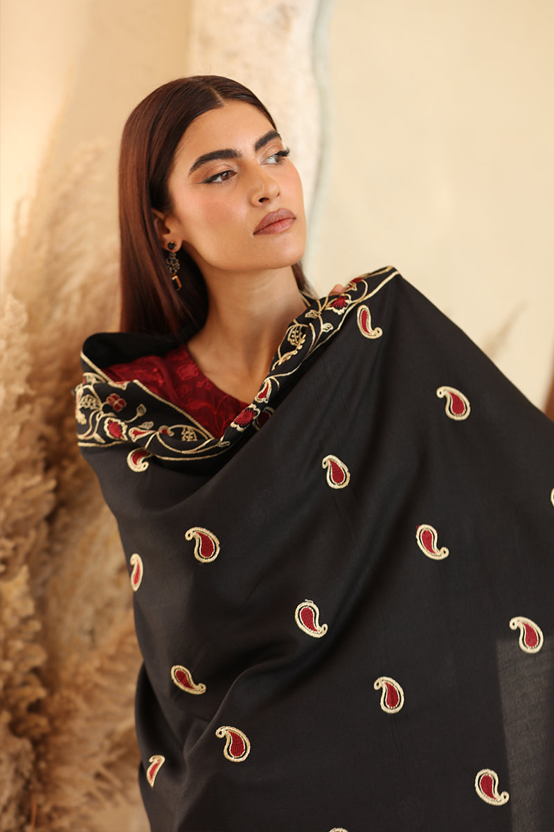 Woman wearing a black embroidered scarf against a neutral background