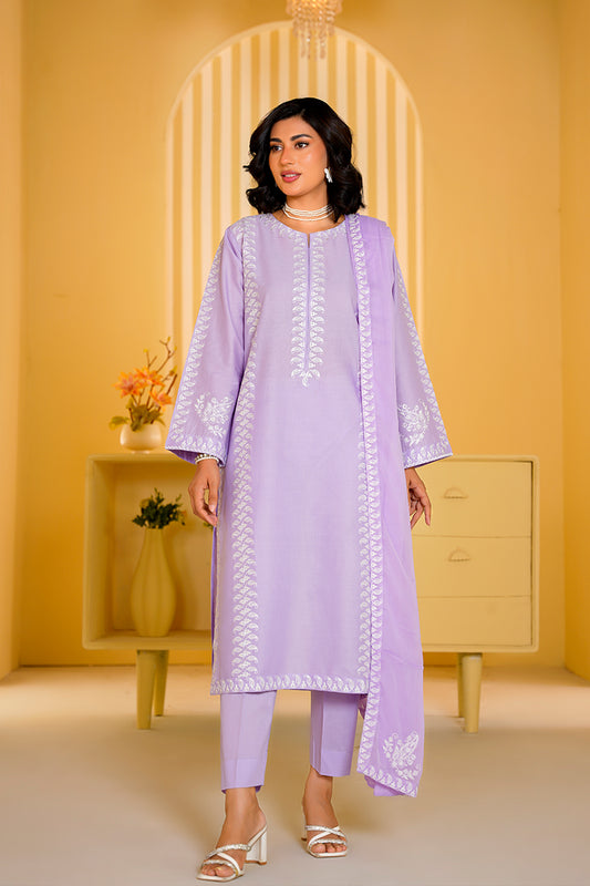 Woman wearing a light purple traditional outfit with white embroidery in a yellow room.