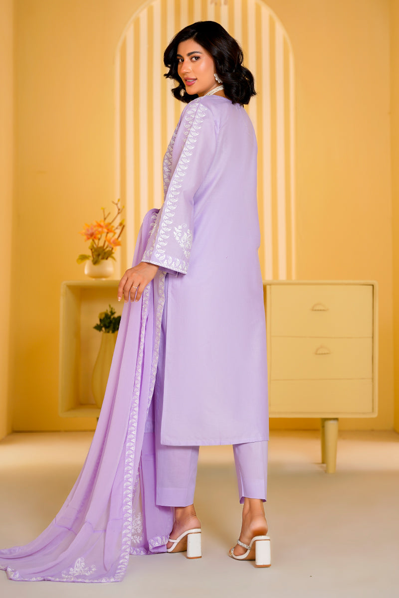 Woman wearing a light purple outfit with white embroidery in a room with yellow walls and furniture.