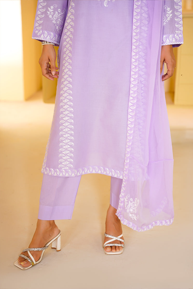 Lavender outfit with white embroidery on a beige background