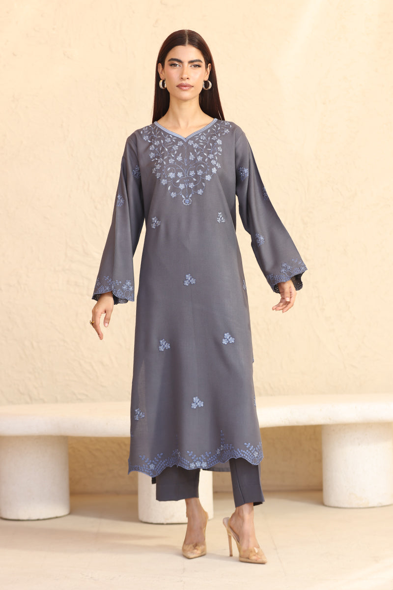 Woman wearing a gray embroidered kurta with pants against a beige background
