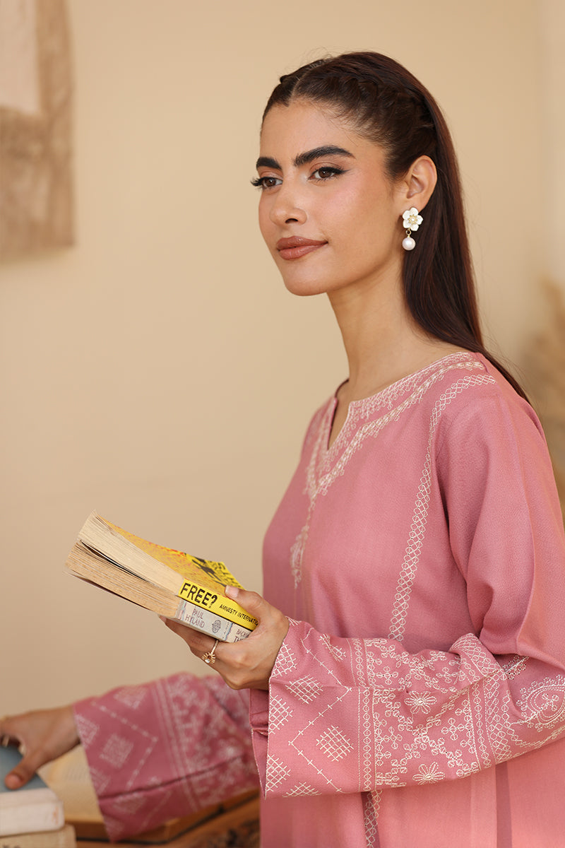 Woman in a pink traditional outfit holding a book with a yellow cover.