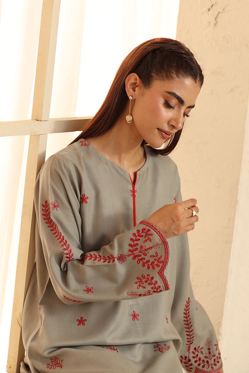 Woman wearing a gray traditional outfit with red embroidery in a bright setting