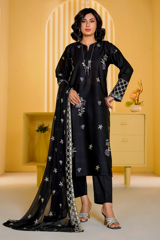 Woman wearing a black traditional outfit with floral patterns in a yellow room.