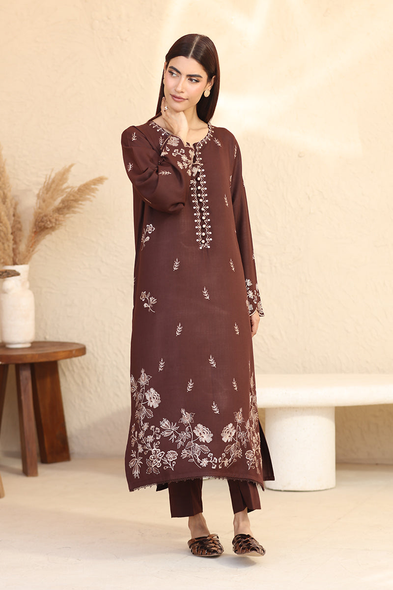 Woman wearing a brown embroidered outfit in a minimalistic setting