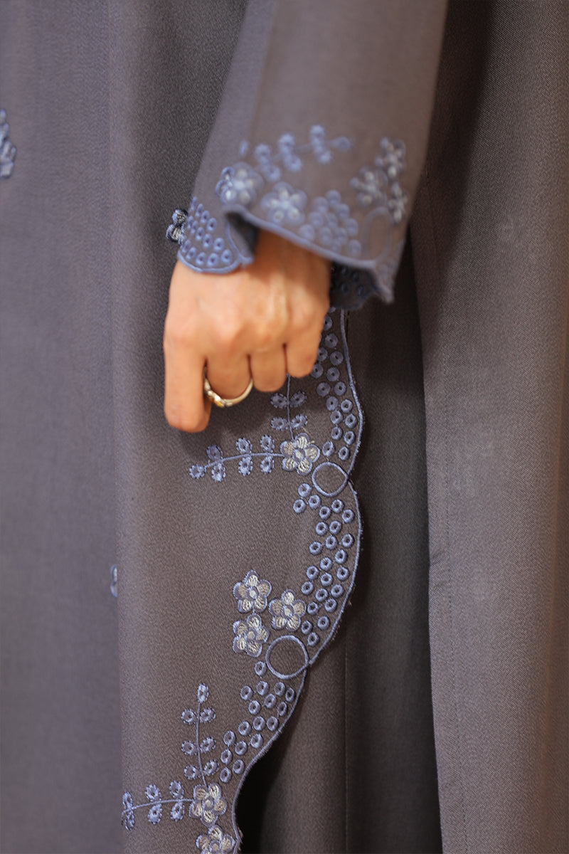 Close-up of a gray embroidered garment with floral patterns.