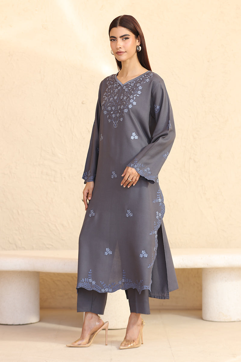 Woman wearing a gray embroidered outfit on a beige background