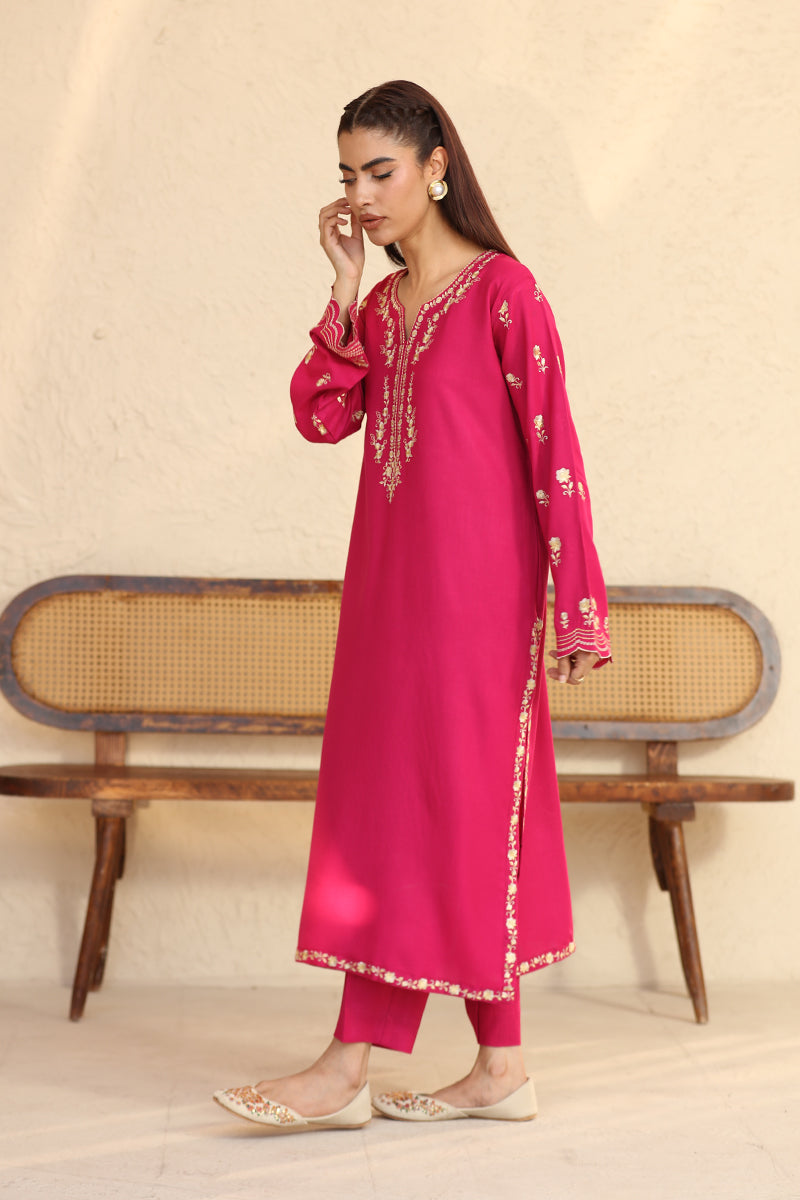 Woman wearing a pink embroidered outfit with a beige background