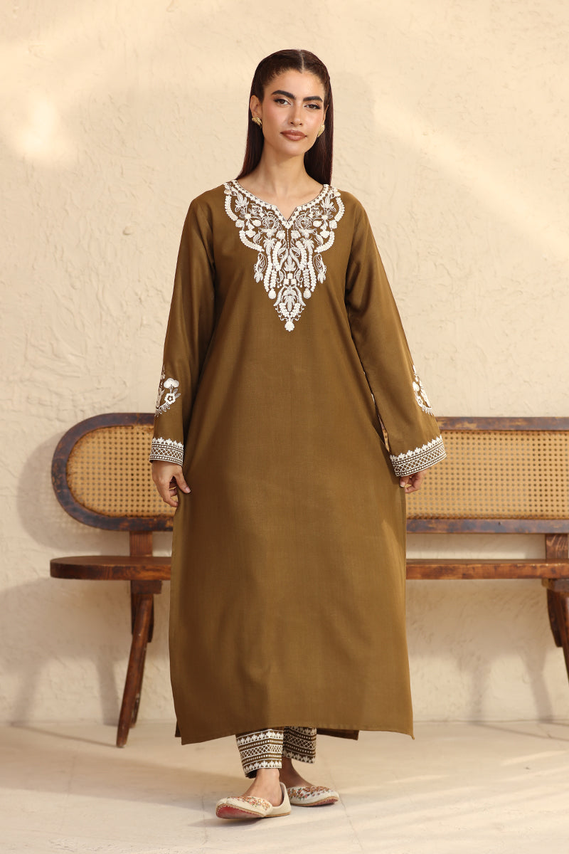Woman wearing a brown kurta with white embroidery in a minimalistic setting