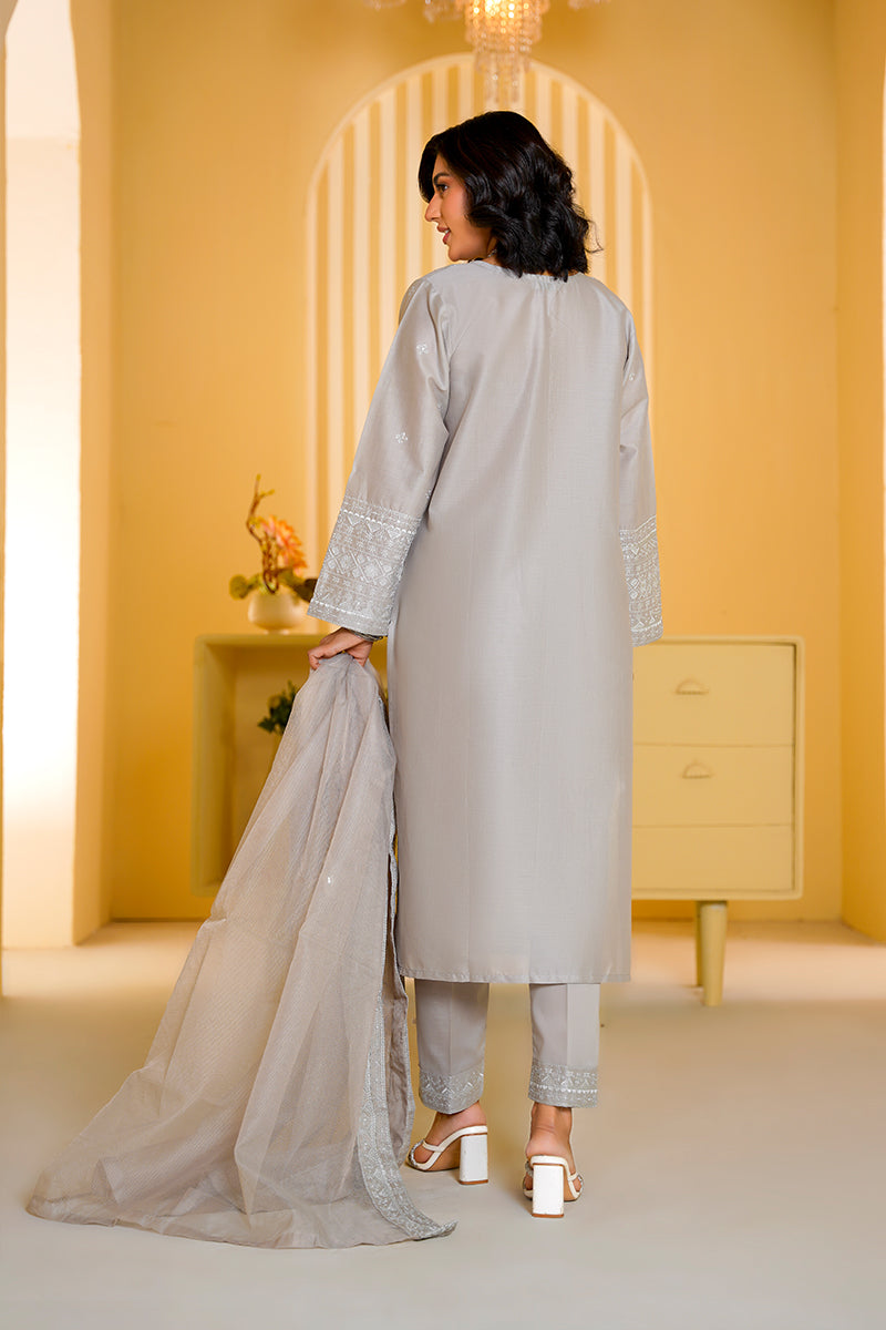 Woman in a gray traditional outfit standing in a room with yellow walls and a white rug.