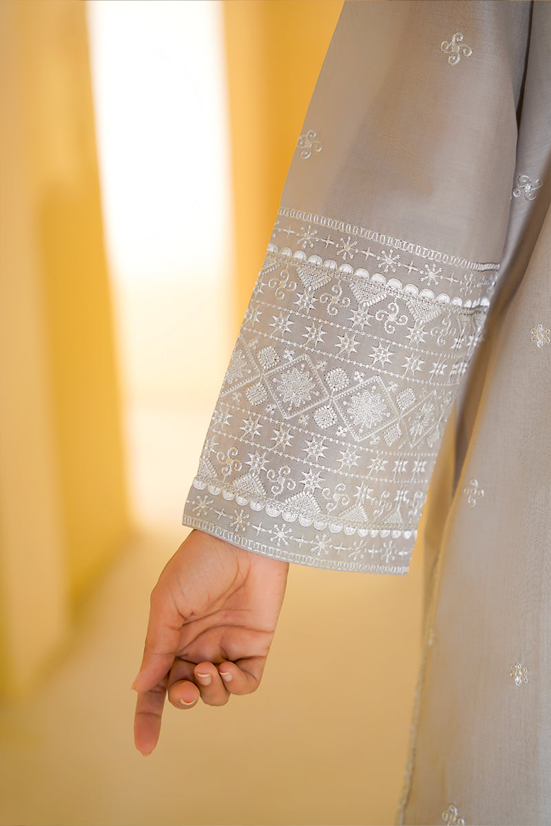 Close-up of a hand holding a fabric with intricate patterns against a blurred yellow background
