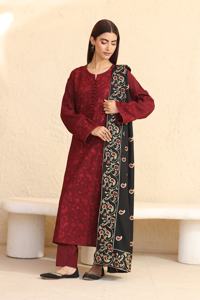 Woman wearing a red traditional outfit with a black and red patterned dupatta against a beige background