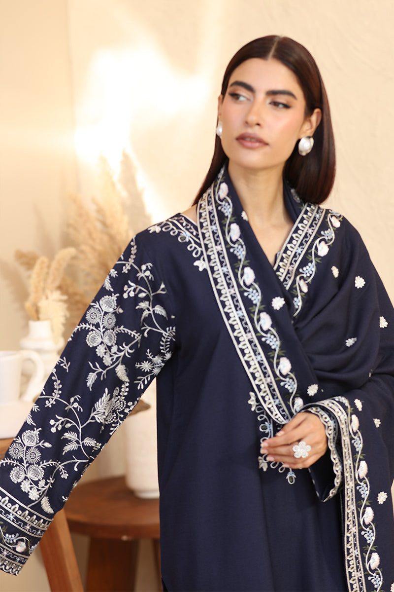 Woman wearing a navy blue embroidered outfit with a white background