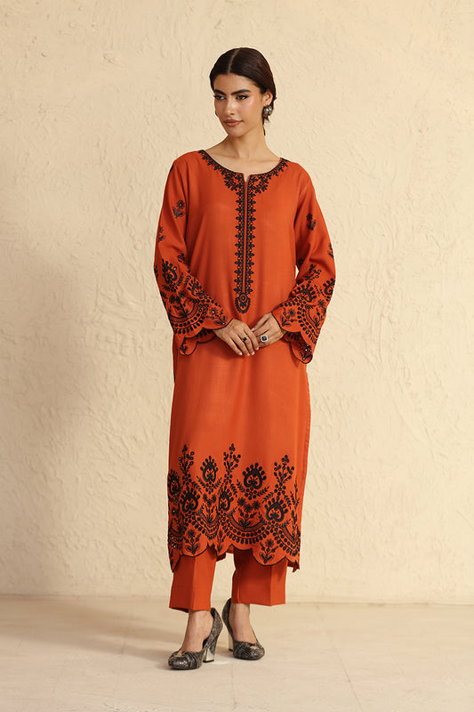 Woman wearing an orange embroidered outfit against a beige background