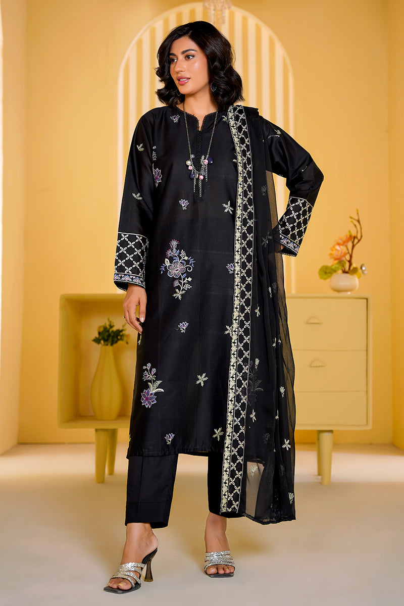 Woman wearing a black embroidered outfit in a bright room with yellow walls.