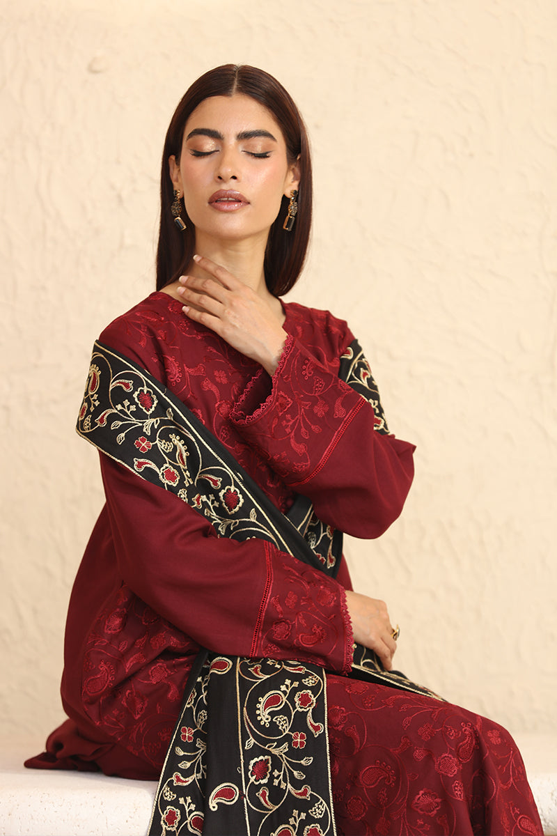 Woman wearing a red traditional outfit with black and gold embroidery on a beige background
