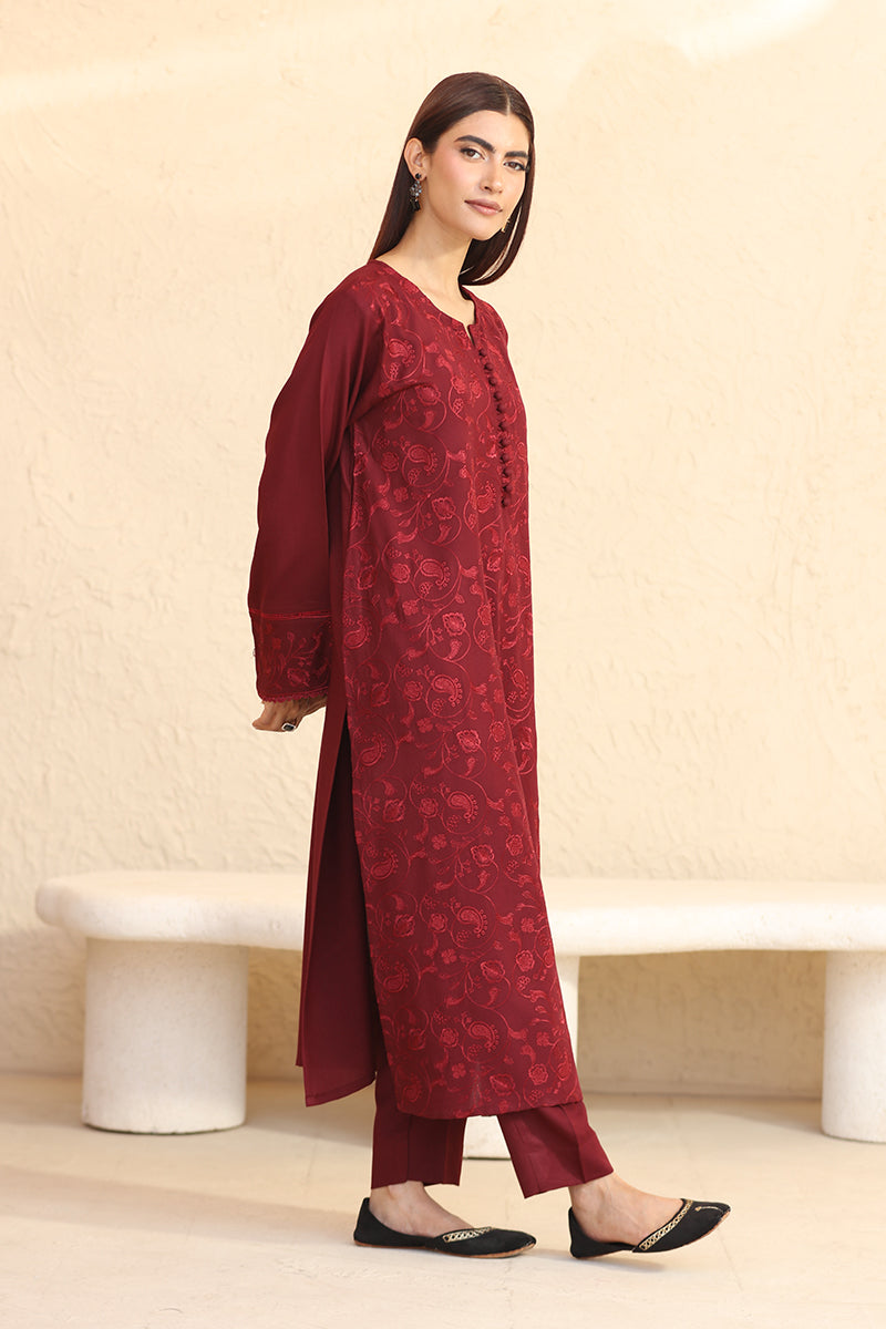 Woman wearing a red patterned kurta with matching pants against a beige background