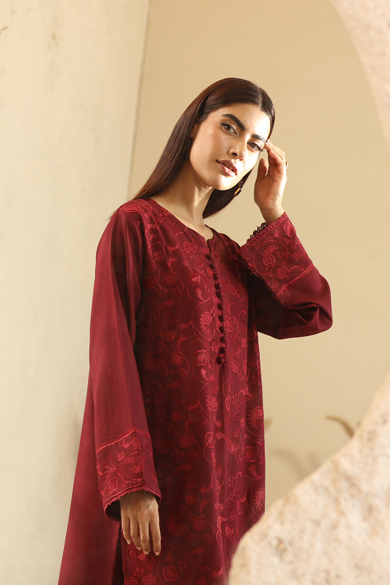 Woman wearing a red embroidered dress against a neutral background