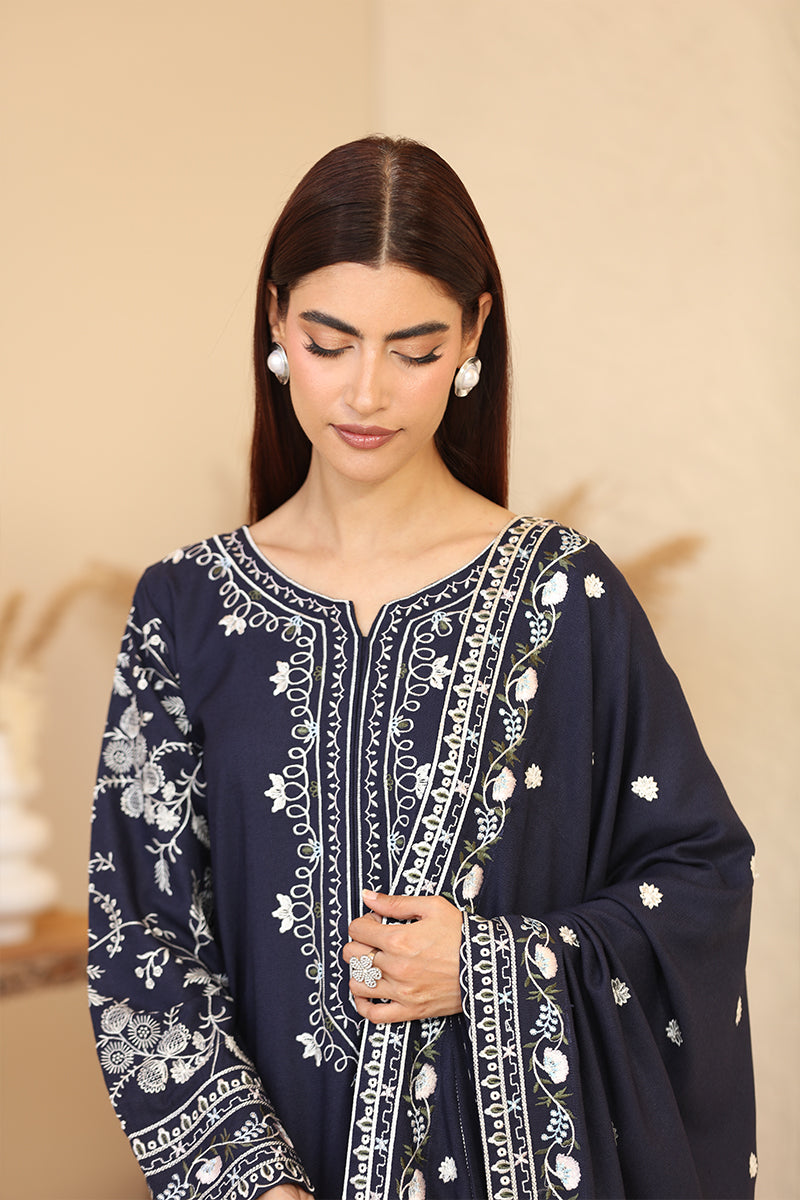 Woman wearing a navy blue embroidered outfit against a beige background