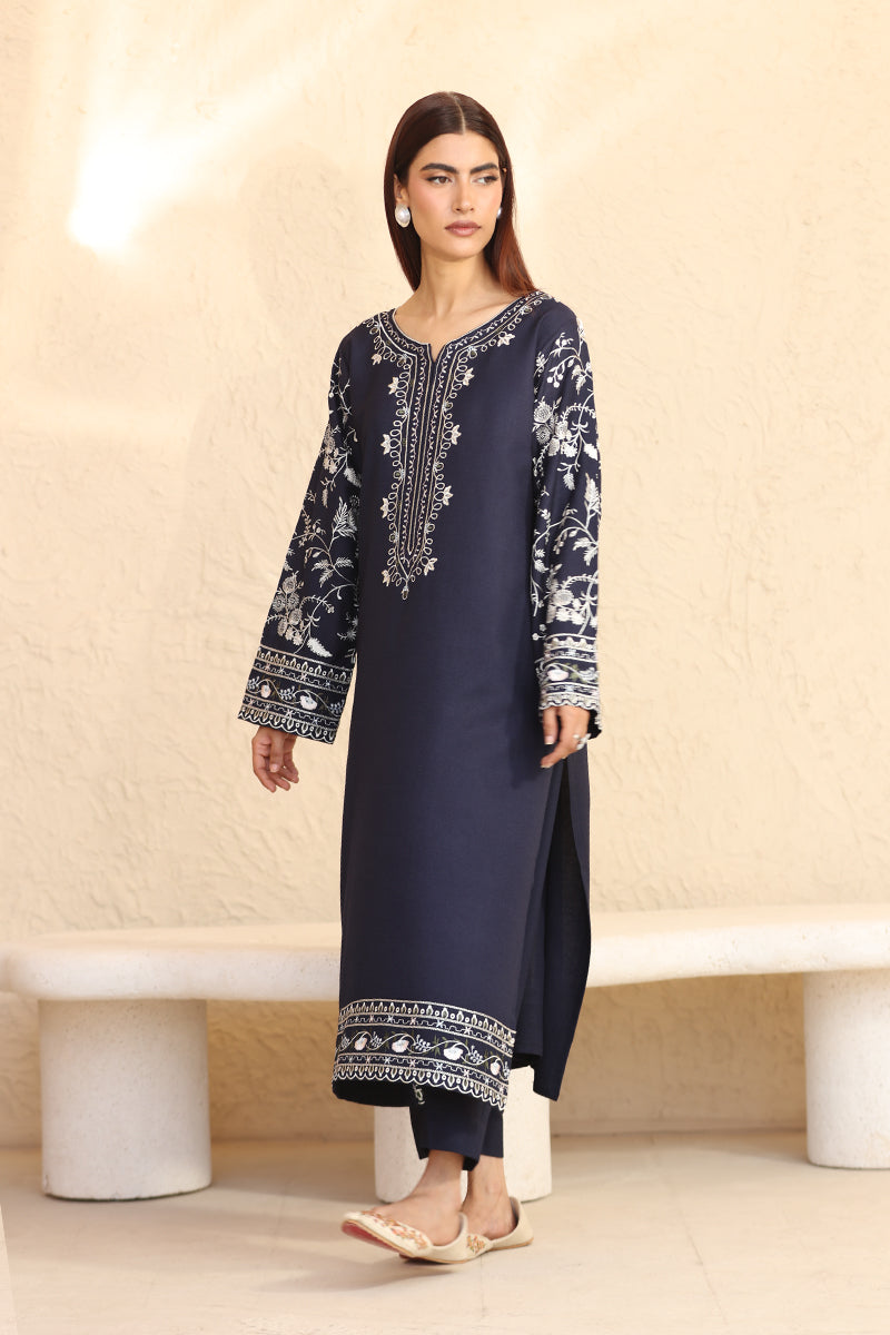 Woman wearing a navy blue embroidered outfit on a beige background