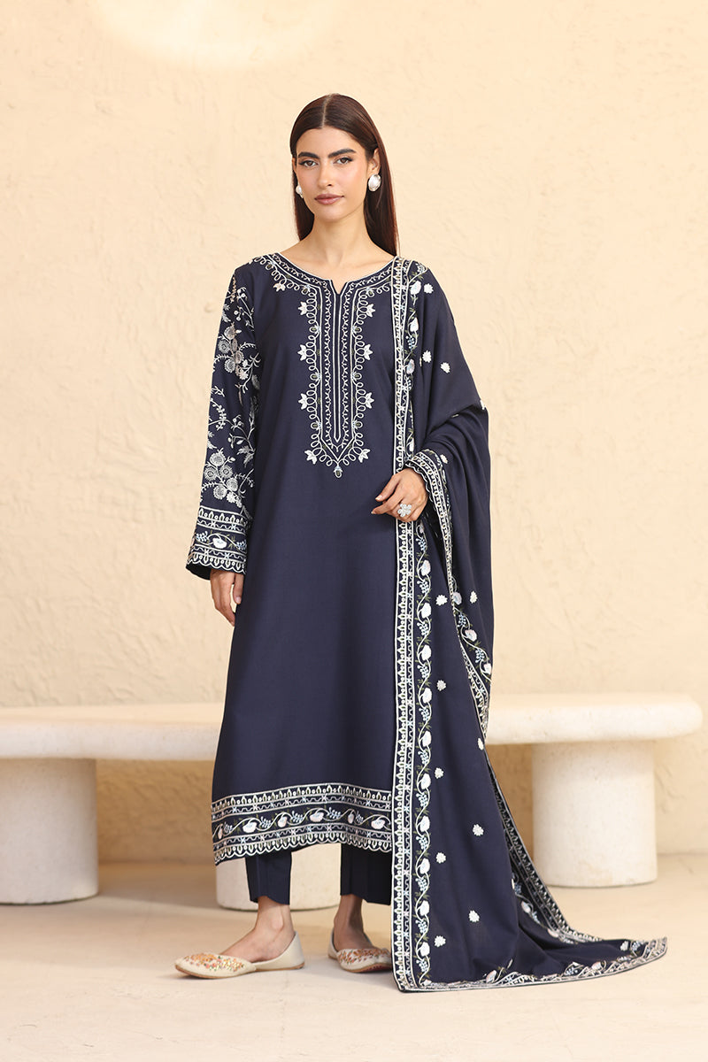 Woman wearing a navy blue embroidered outfit with a beige background