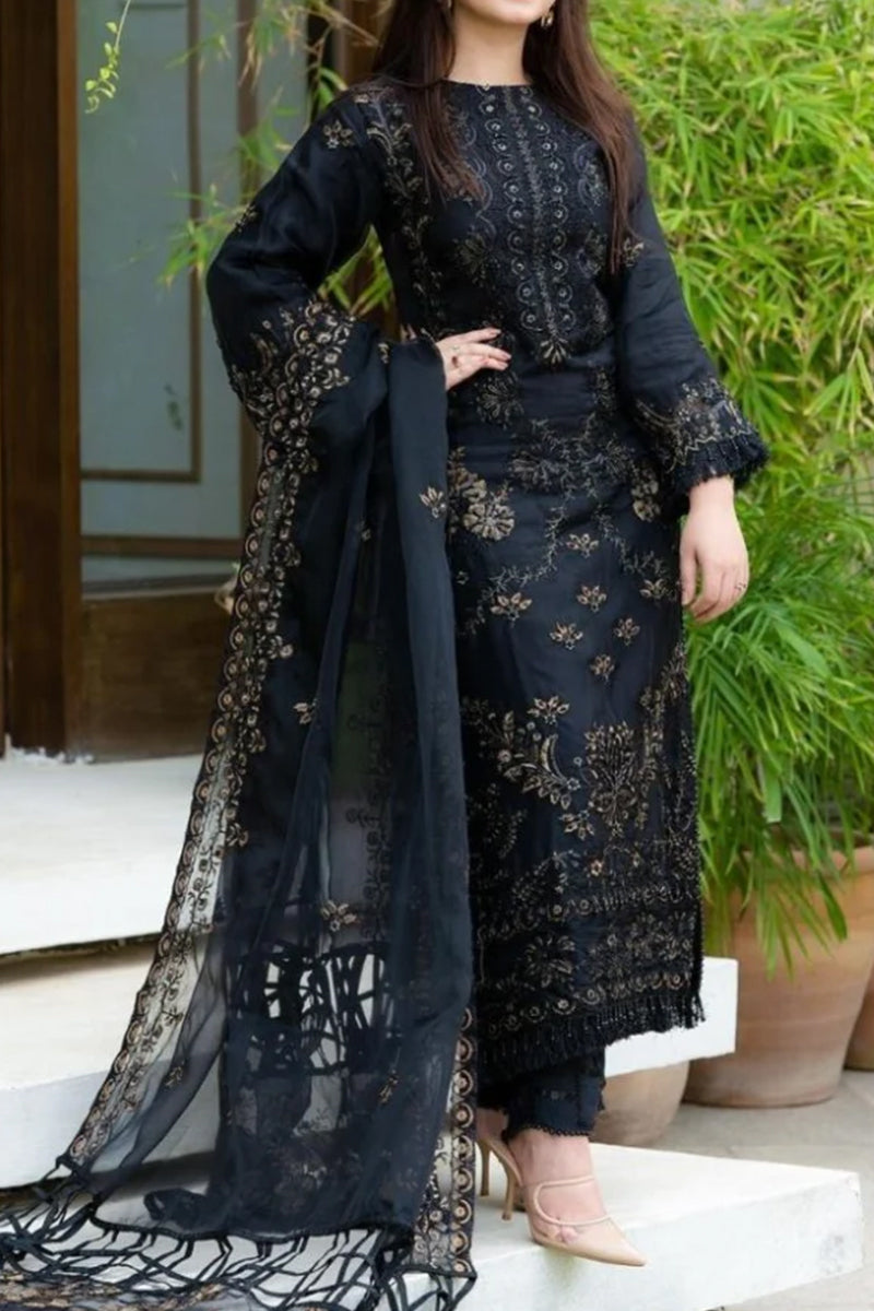 Woman wearing a black embroidered outfit with a sheer overlay in an outdoor setting.