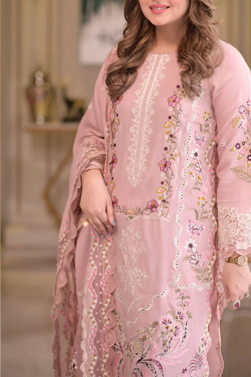 Woman wearing a pink embroidered dress with a blurred indoor background