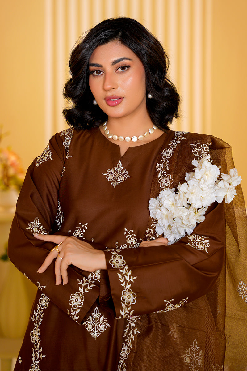 Woman wearing a brown embroidered dress with white flowers against a yellow background
